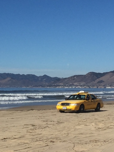 Yellow taxi driving on the beach 